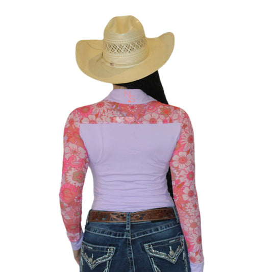 Woman wearing a light pink and peach mesh rodeo shirt with floral sleeves showing the back of the shirt.