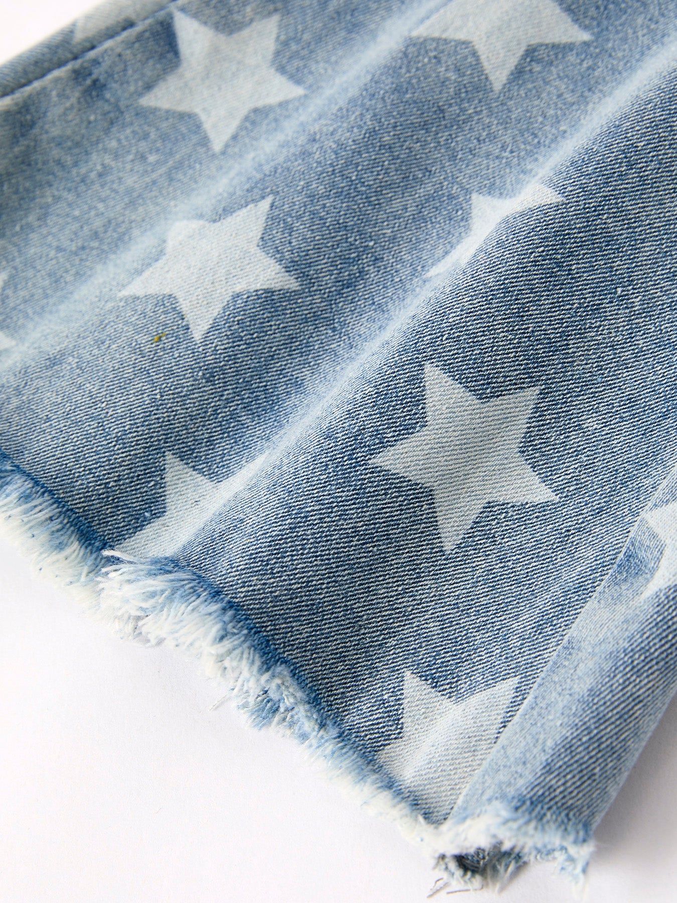 Flared western toddler and kids jeans with star pattern on a white background showing the frayed hem.
