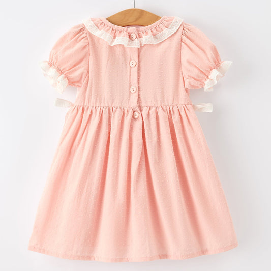 Back of pink dress with white collar and buttons on a hanger against a white background