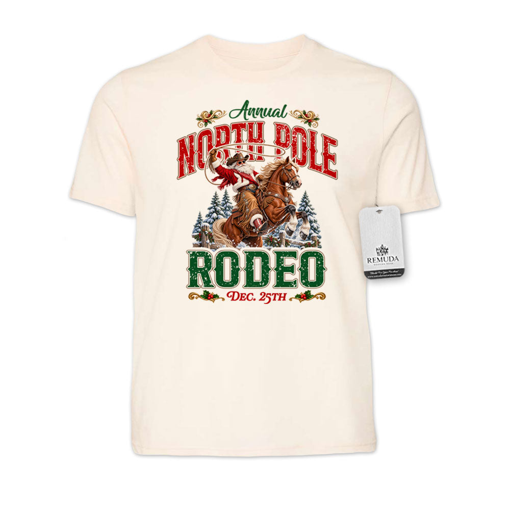 Solid Natural-color adult unisex short sleeve T-shirt featuring a festive North Pole Rodeo Christmas design with Cowboy Santa riding a rearing horse, snowy pine trees, vintage red and green Western lettering, December 25th details, and a classic crewneck style.