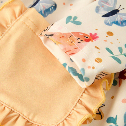 Close-up of a kids yellow dress with chicken and butterfly patterns and ruffled pockets