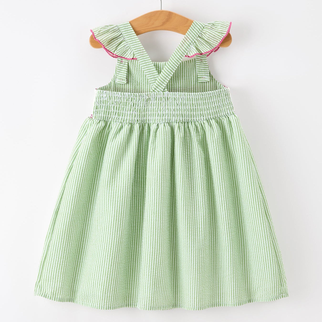 Green striped dress on a wooden hanger against a white background