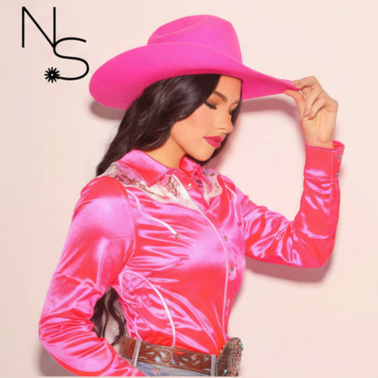 Woman wearing a bright pink cowboy hat and shirt on a light background