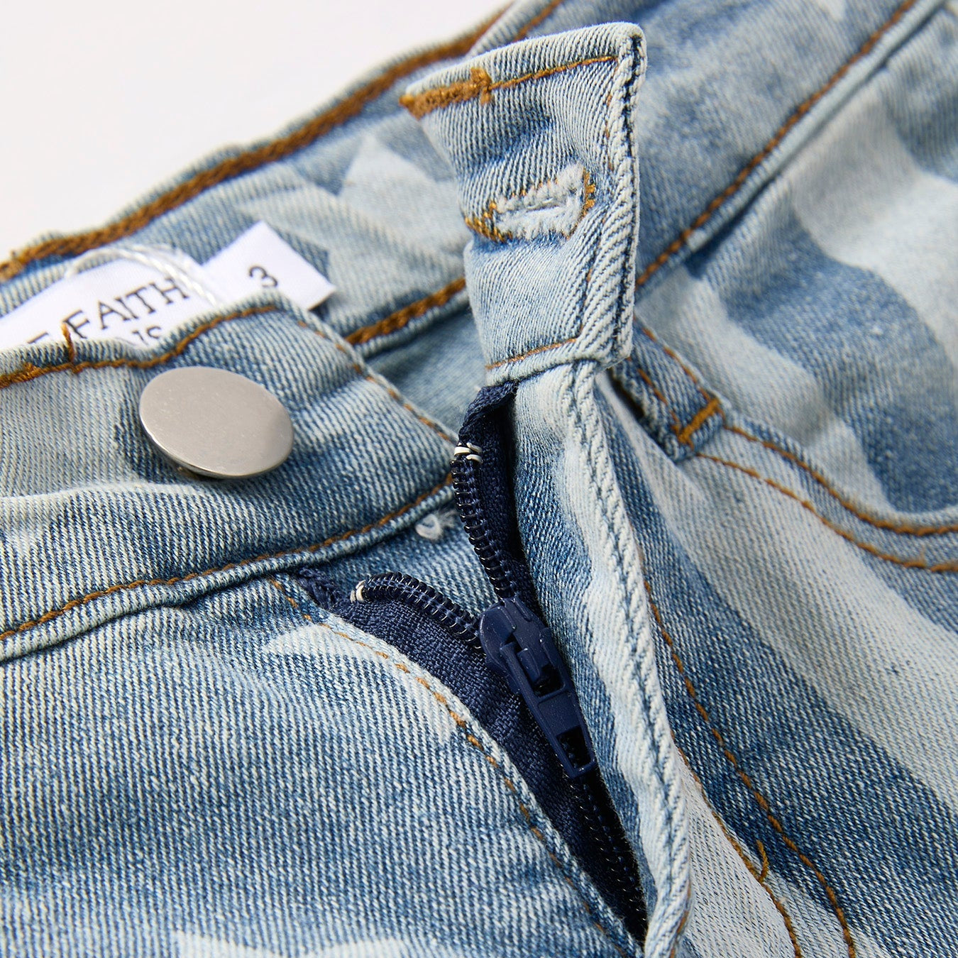 Close-up of a western denim flare  jeans with a star pattern and a button.