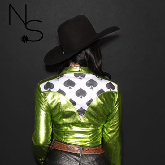 Woman in a green metallic rodeo shirt with black and white spade designs showing the back of the shirt on a black background.