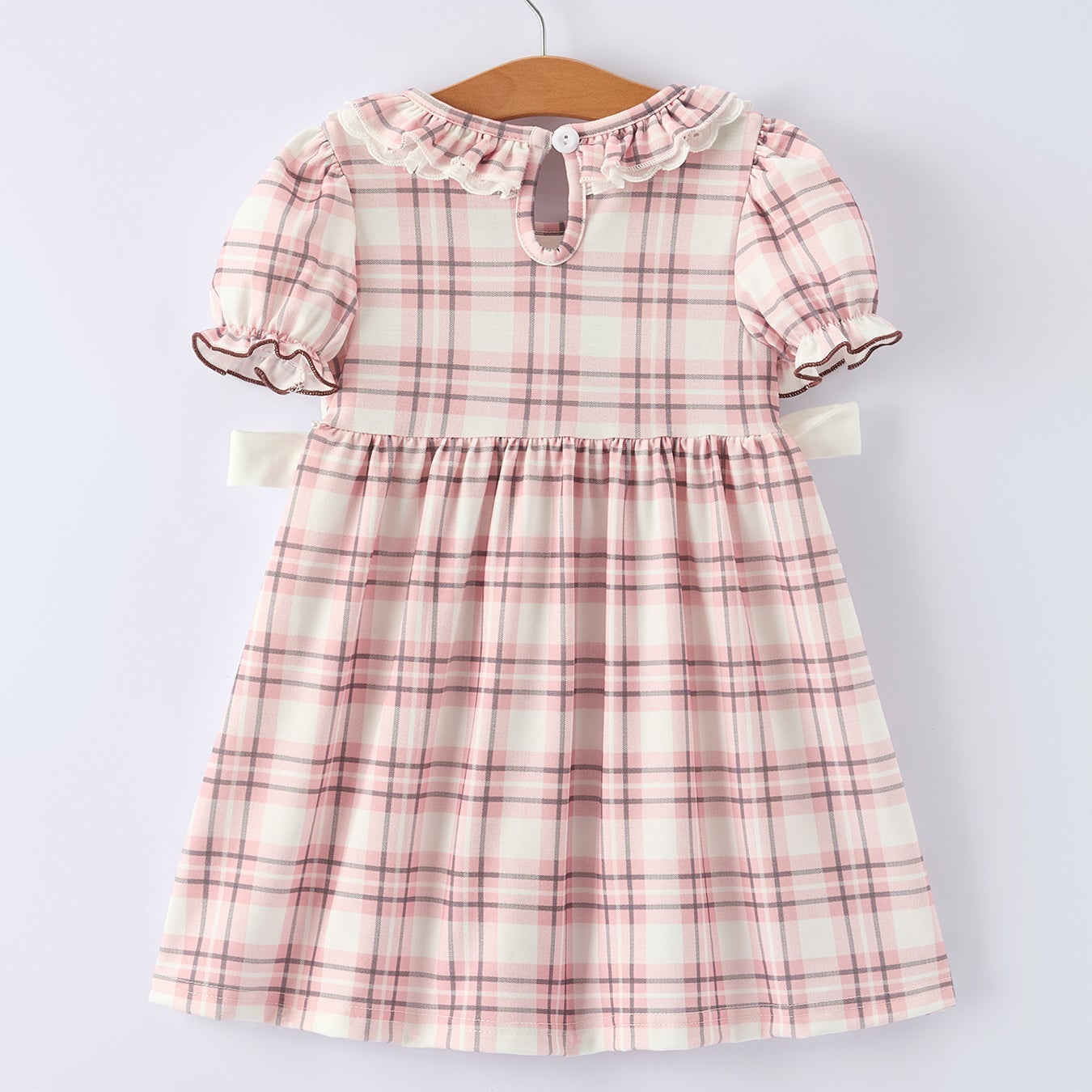 Back of pink plaid dress with horse design on a hanger against a white background