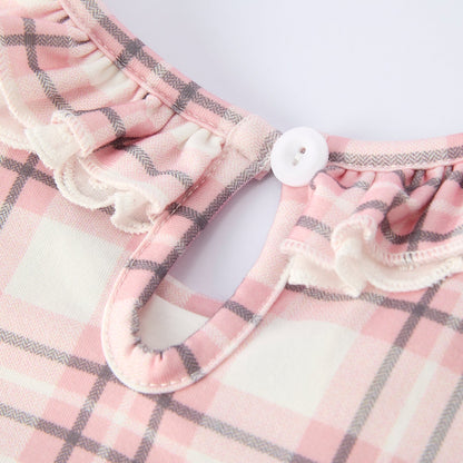 Back closure button of pink plaid dress with horse design on a hanger against a white background