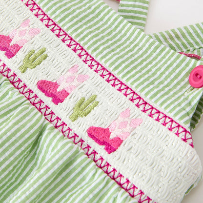 Close up of embroidery on green striped western boots and cactus baby romper with pink accents on a white background