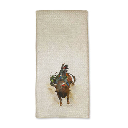 A vibrant western rodeo style kitchen hand towel featuring a bull rider on a bucking bull. Comes in a cream color. The design captures the spirit of rodeo and western culture.