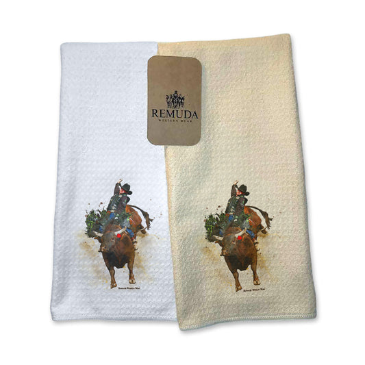 A set of vibrant western rodeo style kitchen hand towels featuring a bull rider on a bucking bull. Comes in cream and white colors. The design captures the spirit of rodeo and western culture.