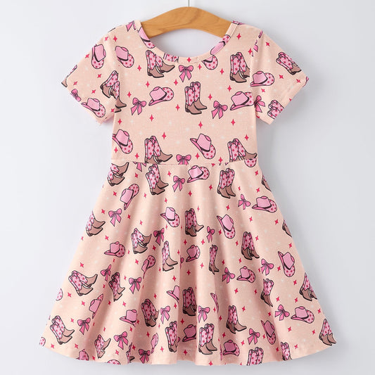 Pink dress with cowboy boot and bow pattern on a hanger against a white background