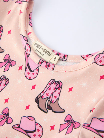 Pink shirt with cowboy boot, hat, and bow pattern, featuring a visible brand label.