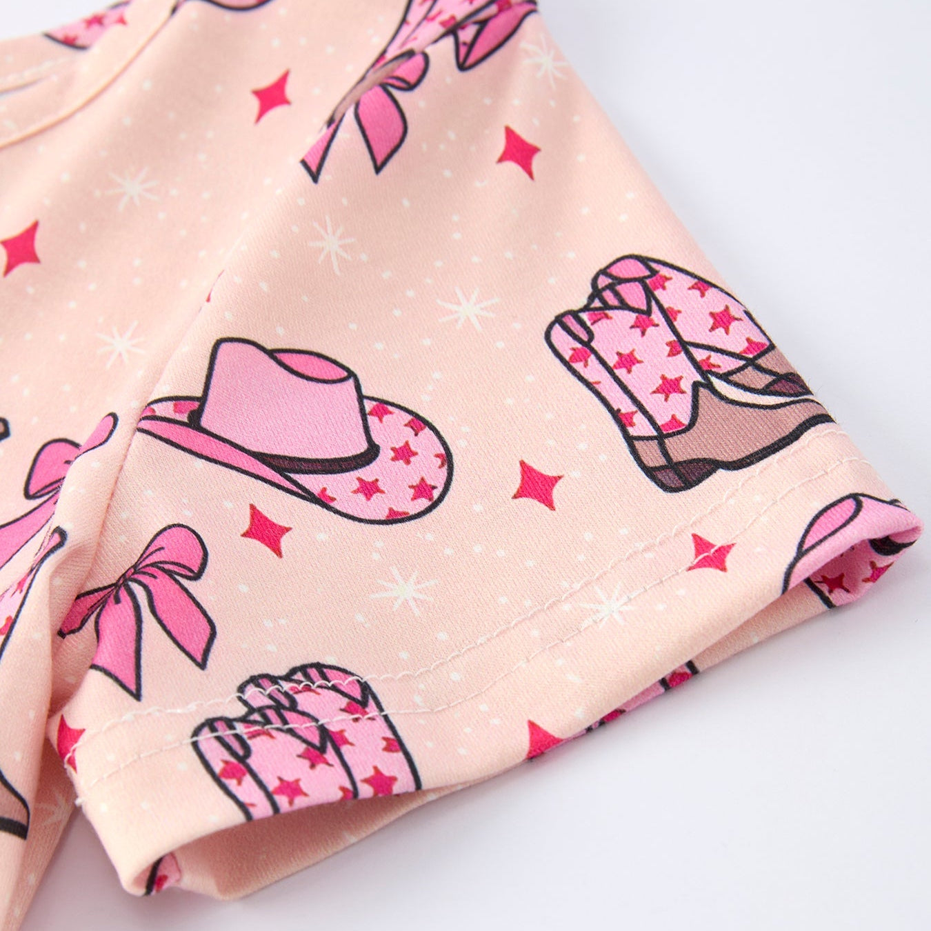 Girls dress with pink cowboy hat, boots, and bow designs on a light background