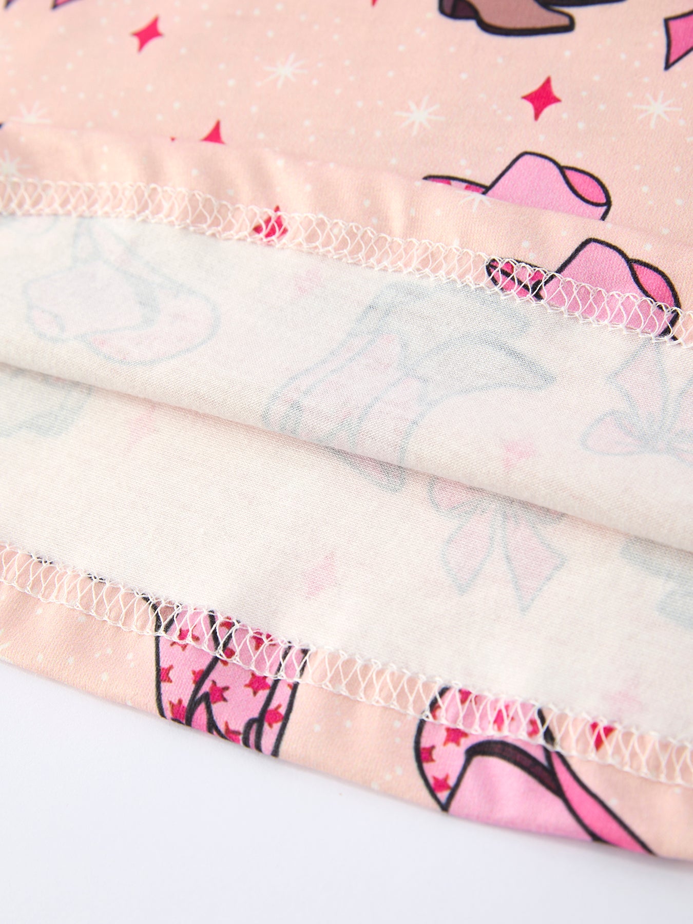 Close-up of girls dress with pink cowboy hats and sunglasses pattern on a light background