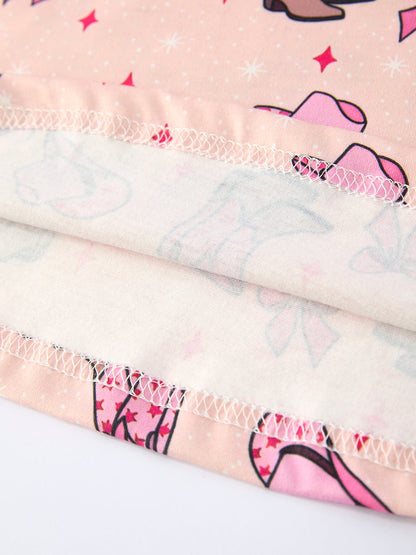 Close-up of girls dress with pink cowboy hats and sunglasses pattern on a light background