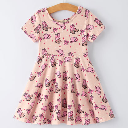 Pink dress with cowboy boot and bow pattern on a hanger against a white background