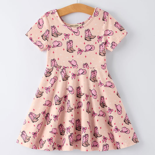 Pink dress with cowboy boot and bow pattern on a hanger against a white background