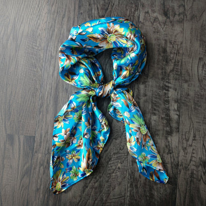 A western Wild Rag with Multi-colored daisies scattered all over a blue background.