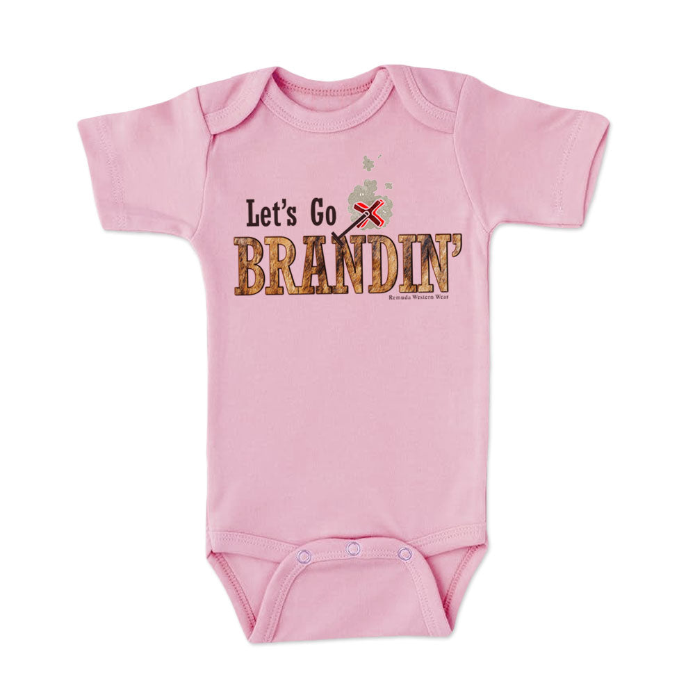 A stylish western-themed light pink colored infant short sleeve one piece romper bodysuit featuring the phrase 'Let's Go Brandin'' prominently printed in bold, weathered letters across the chest. Above the shirt is is an illustration of a branding iron, evoking a rustic cowboy aesthetic. Kids Western wear, Ranch wear and Rodeo wear.