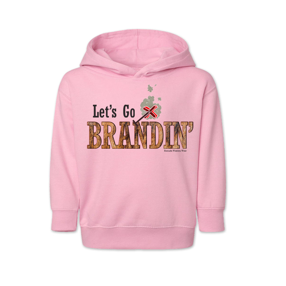 A vintage light pink colored toddler hoodie with the phrase 'Let's Go Brandin'' printed in bold western letters across the chest. Above the text is an illustration of a classic western-style branding iron, emitting a faint glow of heat. The branding iron features a distinctive 'X' emblem, reminiscent of cattle branding. A great shirt for kids western wear, ranch wear, or rodeo wear.