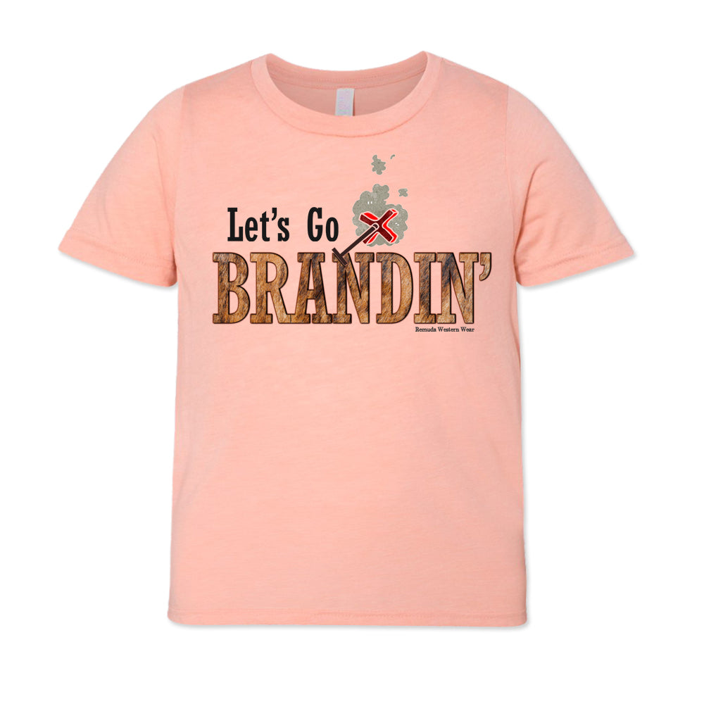 A stylish western-themed peach colored youth t-shirt featuring the phrase 'Let's Go Brandin'' prominently printed in bold, weathered letters across the chest. Above the shirt is is an illustration of a branding iron, evoking a rustic cowboy aesthetic. Kids Western wear, Ranch wear and Rodeo wear.