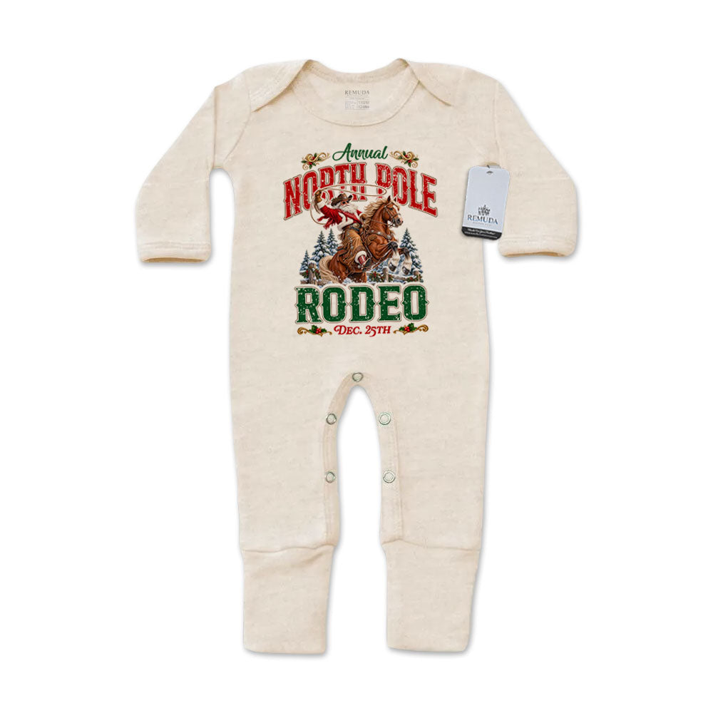 Oatmeal-colored infant one-piece footed pajamas featuring a festive North Pole Rodeo Christmas graphic with cowboy Santa riding a rearing horse, red and green lettering, long sleeves, and snap closures.