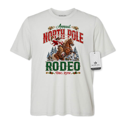 Solid Silver-color adult unisex short sleeve T-shirt featuring a festive North Pole Rodeo Christmas design with Cowboy Santa riding a rearing horse, snowy pine trees, vintage red and green Western lettering, December 25th details, and a classic crewneck style.