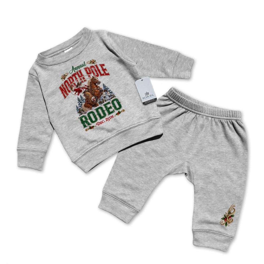 Heather Gray-colored infant two-piece sweatsuit featuring a long sleeve pullover sweatshirt with Cowboy Santa riding a bucking bronc in a festive North Pole Rodeo Christmas design, paired with matching elastic-waist sweatpants with a decorative holiday design.