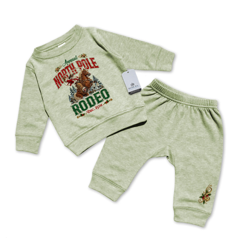 Heather sage green infant two-piece sweatsuit featuring a long sleeve pullover sweatshirt with Cowboy Santa riding a bucking bronc in a festive North Pole Rodeo Christmas design, paired with matching elastic-waist sweatpants with a decorative holiday design.
