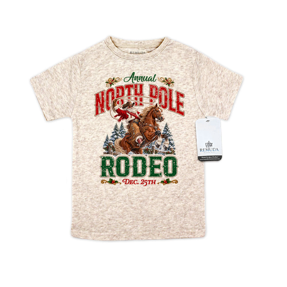 Oatmeal-colored toddler short sleeve T-shirt featuring a festive North Pole Rodeo Christmas design with Cowboy Santa riding a rearing horse, snowy pine trees, vintage red and green rodeo lettering, and December 25th details.