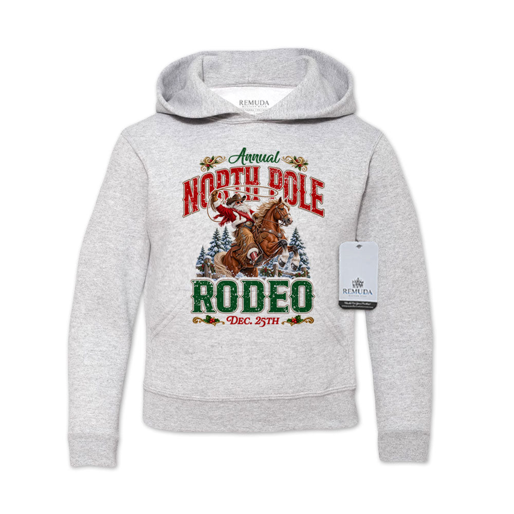 Ash Gray youth pullover fleece hoodie featuring a festive North Pole Rodeo Christmas design with Cowboy Santa riding a rearing horse, snowy pine trees, vintage red and green Western lettering, December 25th details, a front kangaroo pocket, and ribbed cuffs and hem.
