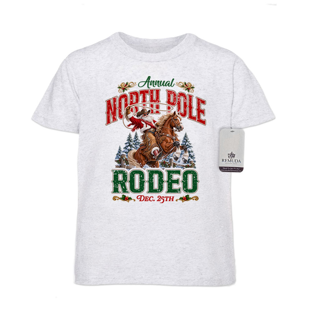 White fleck youth short sleeve T-shirt featuring a festive North Pole Rodeo Christmas design with Cowboy Santa riding a rearing horse, snowy pine trees, vintage red and green Western lettering, December 25th details, and a classic crewneck style.