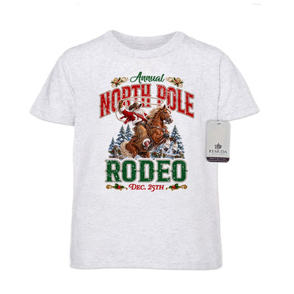 White fleck youth short sleeve T-shirt featuring a festive North Pole Rodeo Christmas design with Cowboy Santa riding a rearing horse, snowy pine trees, vintage red and green Western lettering, December 25th details, and a classic crewneck style.
