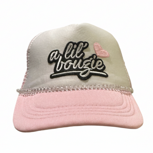 Pink and beige trucker hat with 'a lil bougie' text and heart design on a white background