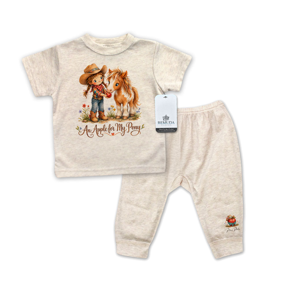 Children's oatmeal colored short sleeve pajama outfit with shirt and pants featuring a cowgirl and horse design on a white background.