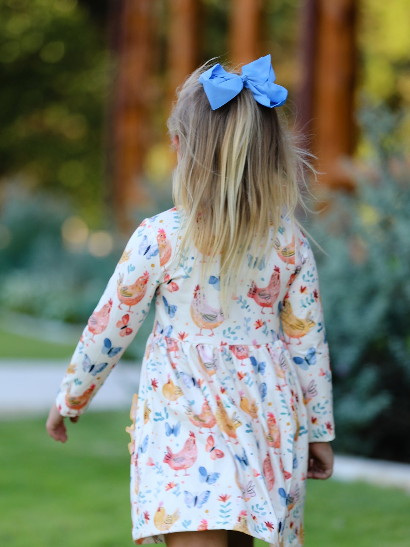 Child wearing a floral dress with long sleeves in an outdoor setting