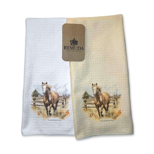 A set of vibrant western style kitchen hand towels featuring a beautiful palomino horse running in a field with a wooden fence behind him. Comes in cream and white colors. The design captures the spirit of western culture.