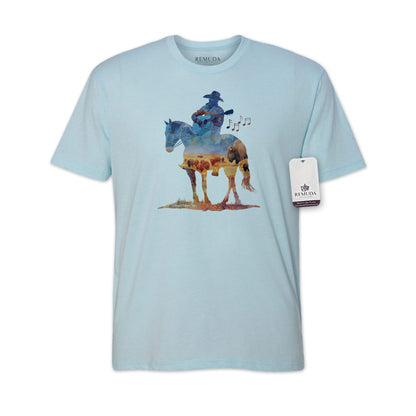 Watercolor-style illustration on a western light blue colored t-shirt showing a cowboy on horseback playing a guitar, with a soft, artistic western aesthetic titled “Where The Buffalo Roam.”