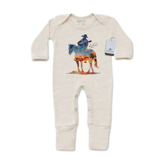 Infant one-piece footed oatmeal colored sleepwear with built-in mittens featuring a watercolor-style design of a cowboy on horseback playing a guitar, titled “Where The Buffalo Roam,” in a soft, artistic western theme.