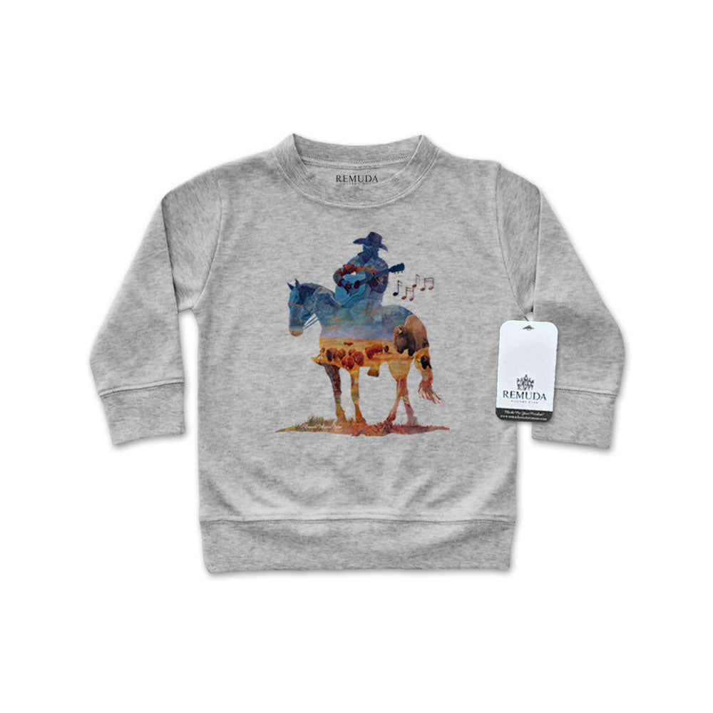 Watercolor-style illustration on an gray colored infant long sleeve pullover showing a cowboy on horseback playing a guitar, titled “Where The Buffalo Roam,” in a soft, artistic western design.